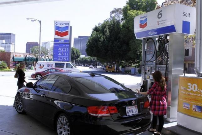 A woman stands at a petrol pump at a Chevron gasoline station in Los Angeles,California April 11, 2011.REUTERS/Fred Prouser